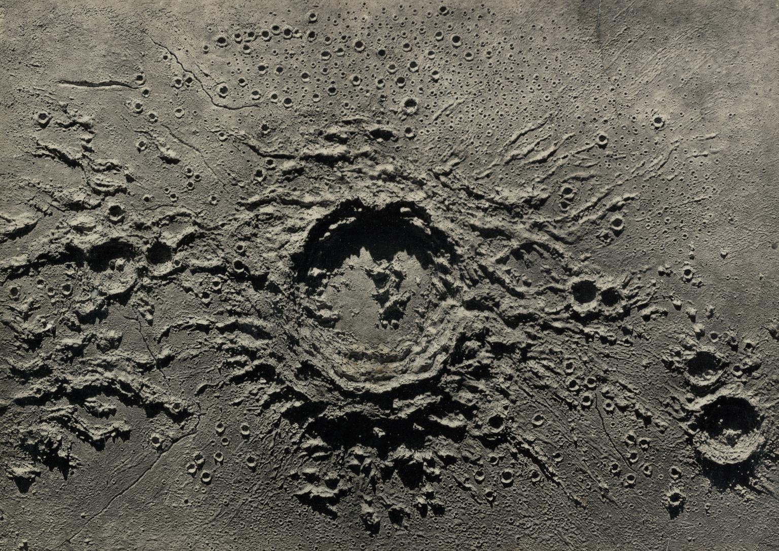 One of two photographs showing obliquely lit a plaster relief model of the lunar crater Copernicus