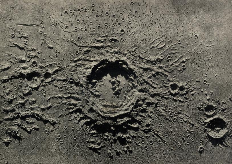 One of two photographs showing obliquely lit a plaster relief model of the lunar crater Copernicus