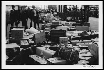 Railway workers standing alongside a large amount of luggage on a platform