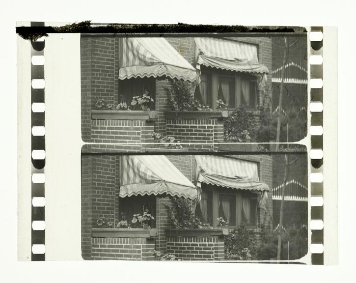 Two frames of silent 65mm positive Paramount black and white film showing the front of a house