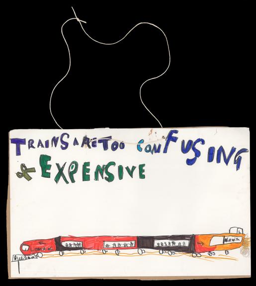 Homemade placard ''trains are too confusing and expensive'' with image of train, designed and made by Eve Wickerson aged