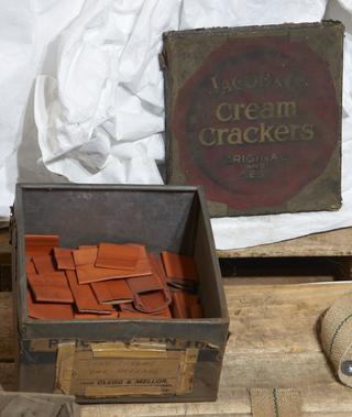 Metal tin containing orange leather hots made for Shaw Jardine