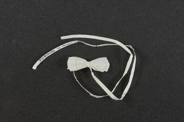 White cotton ribbon tied up as a bow tie, 1935-1950