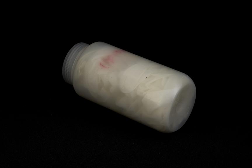 Several long white latex gloves in screw top container