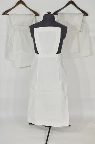 Three white linen aprons with square pin-up bibs and button waists