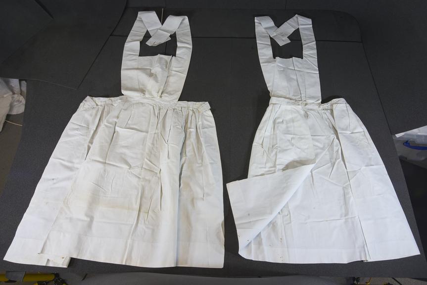 Two linen aprons with square bibs and cross-straps