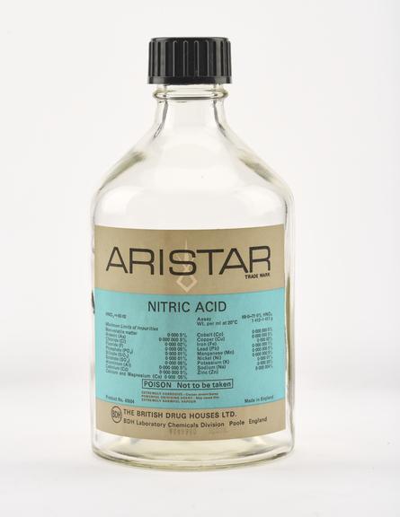An empty clear glass bottle for nitric acid.
