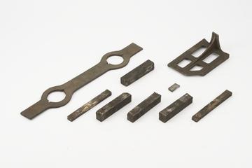 An iron bar about 19 " x 1 3/4" x 1/4" with  swellings for 2 holes about 2 1/8" diameter at 10" centres drifted