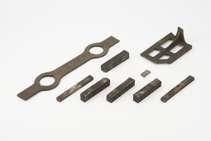 An iron bar about 19 " x 1 3/4" x 1/4" with  swellings for 2 holes about 2 1/8" diameter at 10" centres drifted
