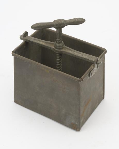 Meat press comprising a rectangular container, yoke, screw, plate and handle