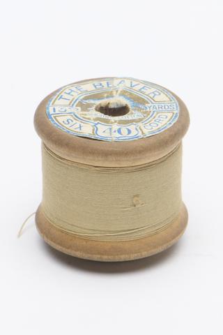 One wooden cotton thread spool with yellow thread, 1920-1970